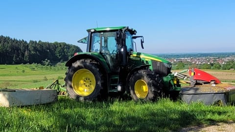Traktor mit Mähwerk bei der Landschaftspflege auf einer Wiese